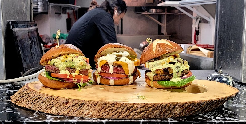 Three burgers on a table with vegan sauces