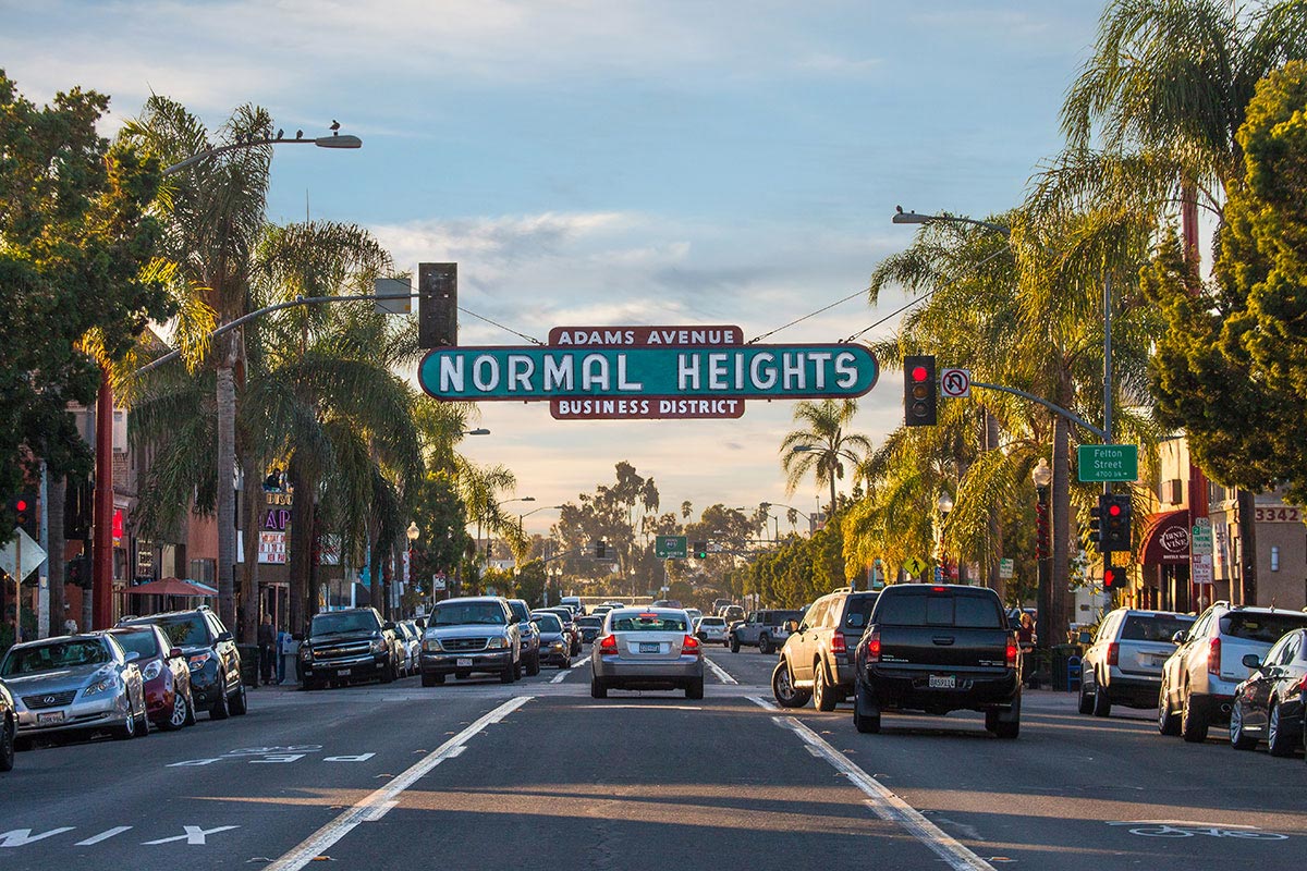 Large sign over a road that reads "Adams Avenue Normal Heights Business District"